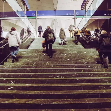 Mehrere Personen gehen die Stufen in einer Bahnhofshalle hinauf.