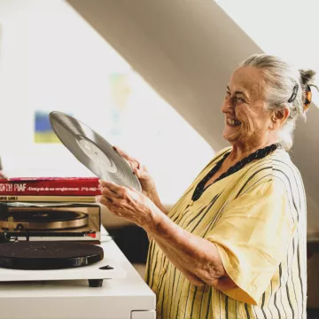 PROMENZ/dragan_dok Person hält eine LP in den Händen und lacht.