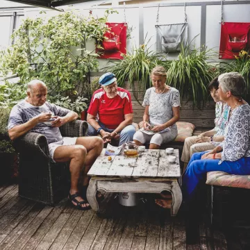 Eine Gruppe von Personen sitzt an einem Tisch und trinkt Tee. 