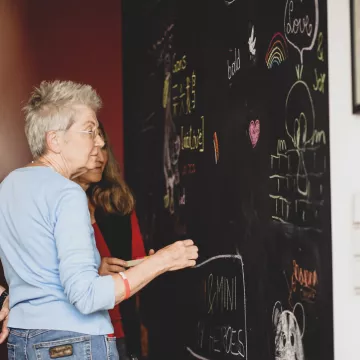 Zwei Personen stehen vor einer Kreidetafel. 