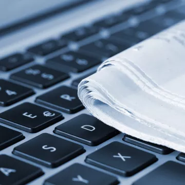 Eine Zeitung liegt auf einer Laptoptastatur. 