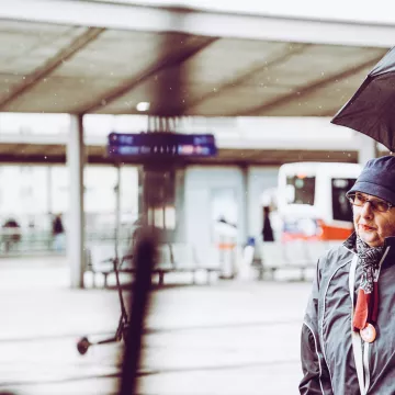 Einer Person steht auf einem Bahnhof. 
