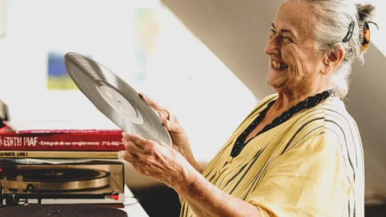 PROMENZ/dragan_dok Person hält eine LP in den Händen und lacht.