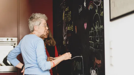 Zwei Personen stehen vor einer Kreidetafel. 