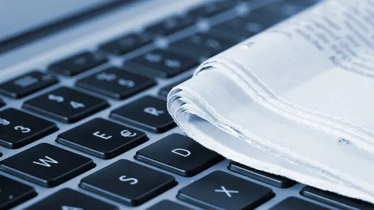 Eine Zeitung liegt auf einer Laptoptastatur. 